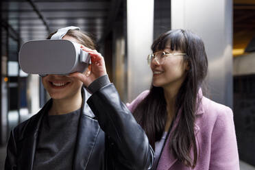Unternehmerin mit Virtual-Reality-Headset und lächelndem Kollegen im Hintergrund - IFRF00865