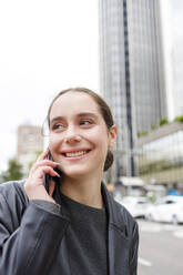 Smiling female entrepreneur looking away while talking on mobile phone - IFRF00870