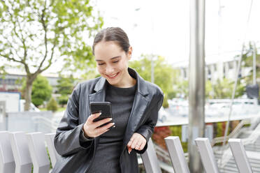 Young businesswoman using mobile phone while leaning on railing - IFRF00883