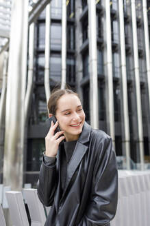 Lächelnde Unternehmerin, die in der Stadt mit einem Mobiltelefon spricht - IFRF00885