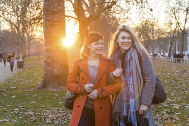 Lächelnde junge Frauen stehen zusammen im Park - WPEF04825
