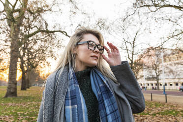 Schöne blonde Frau mit Brille steht im Park - WPEF04827