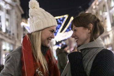 Happy female friends wearing warm clothing looking at each other - WPEF04845