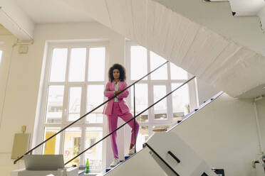 Businesswoman with arms crossed standing on steps in industry - KNSF08695