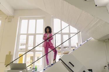 Geschäftsfrau mit verschränkten Armen auf einer Treppe in der Industrie stehend - KNSF08695
