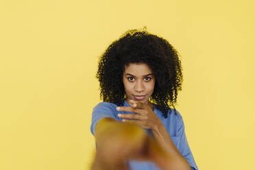 Afro-Frau, die vor einem gelben Hintergrund gestikuliert - KNSF08731