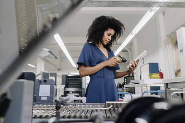 Businesswoman scanning bar code on book in industry - KNSF08810