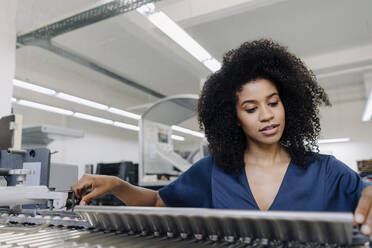 Afro-Unternehmerin beim Einstellen von Maschinen in der Druckindustrie - KNSF08811