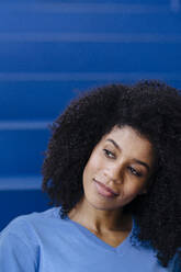 Afro woman contemplating on blue steps - KNSF08815