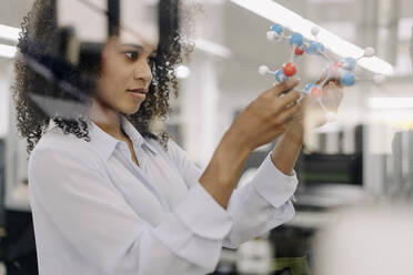 Businesswoman examining molecules model in industry - KNSF08830