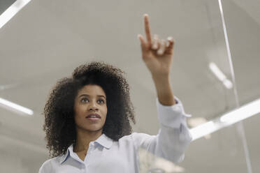 Businesswoman touching glass in industry - KNSF08836