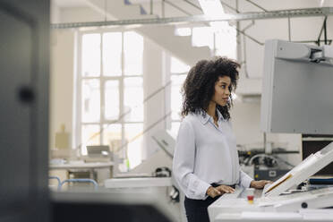 Weibliche Fachkraft, die eine Druckmaschine in der Industrie bedient - KNSF08840