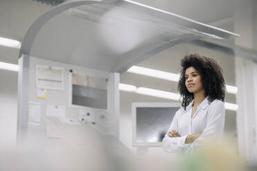 Businesswoman with arms crossed contemplating in industry - KNSF08844