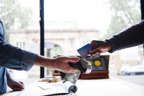 Männlicher Kunde beim Bezahlen mit Kreditkarte in der Werkstatt - ASGF00490