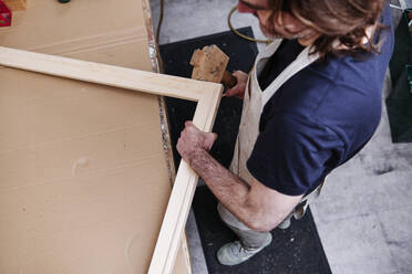 Handwerker mit Hammer bei der Herstellung eines Holzrahmens in der Werkstatt - ASGF00506