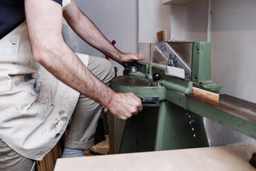 Älterer Handwerker bei der Arbeit in der Werkstatt mit Maschinen - ASGF00510
