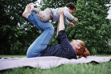 Mutter fasst Sohn beim Spielen im Park am Bein an - ASGF00557