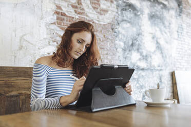 Businesswoman working on graphic tablet at cafe - MTBF01025