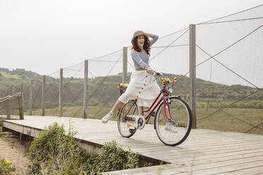Unbekümmerte Frau fährt mit dem Fahrrad auf der Seebrücke - MTBF01037