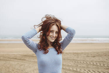 Beautiful woman with head in hand standing at beach - MTBF01039