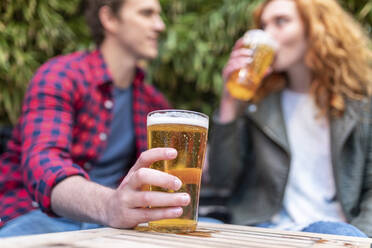 Mann hält Bierglas, während er mit seiner Freundin in einer Kneipe sitzt - WPEF04846
