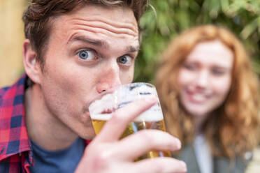 Mann mit hochgezogenen Augenbrauen trinkt Bier in einer Kneipe - WPEF04847