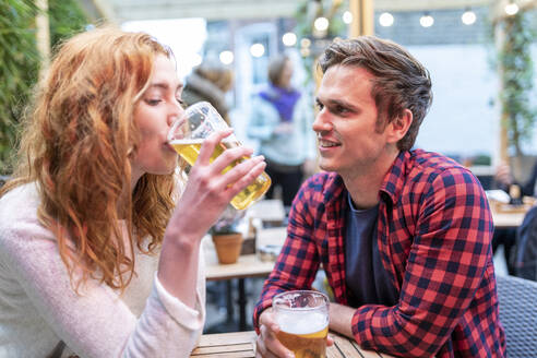 Mann sieht seine Freundin beim Biertrinken in der Kneipe an - WPEF04854