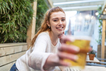 Young woman showing beer glass at pub - WPEF04861