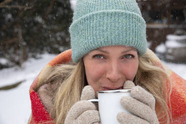 Lächelnde reife Frau beim Kaffeetrinken im Winter - FVDF00230