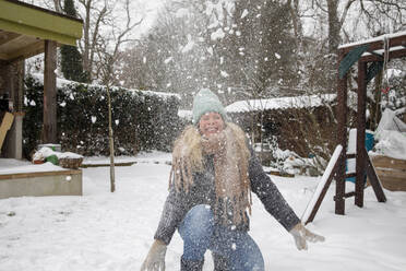 Happy mature woman playing with snow at backyard - FVDF00233