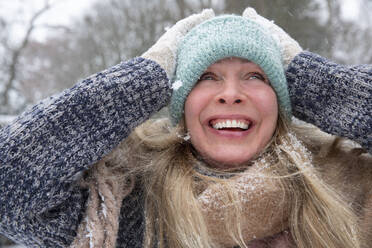 Ältere Frau mit Strickmütze, die lachend wegschaut, im Winter - FVDF00235