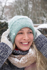 Mature woman wearing knit hat laughing while looking away - FVDF00242