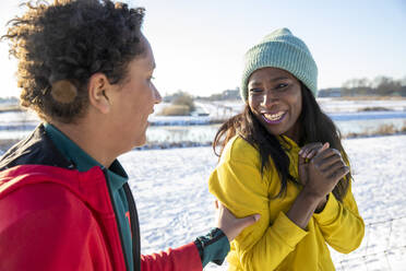 Cheerful mature woman wearing knit hat looking at son during winter - FVDF00254