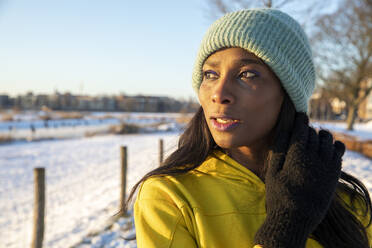 Beautiful mature woman wearing blue knit hat while looking away - FVDF00271