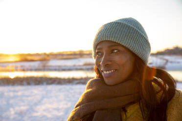 Smiling beautiful woman wearing scarf during winter while looking away - FVDF00282