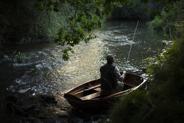 Mann beim Fliegenfischen vom Boot aus auf dem Fluss - CAIF30673