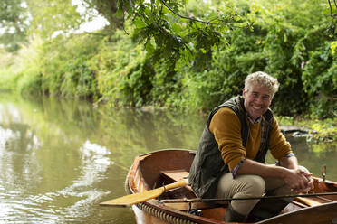 Portrait happy man fly fishing in boat on river - CAIF30699