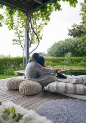 Zärtliches Paar kuschelt auf Kissen auf einer Luxus-Terrasse - CAIF30718