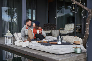 Verliebtes Paar entspannt sich mit Kaffee auf Terrassenkissen - CAIF30720