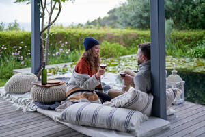 Couple enjoying wine on luxury patio cushions - CAIF30724