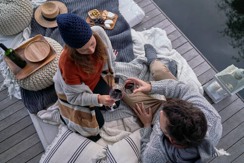 Couple enjoying wine and cheese on patio cushions - CAIF30725