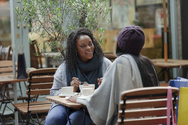 Mutter und Tochter unterhalten sich und genießen das Mittagessen am Terrassentisch eines Cafés - CAIF30773