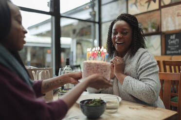 Glückliche Mutter und Tochter feiern Geburtstag mit Kuchen im Café - CAIF30781