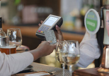 Nahaufnahme eines Kunden, der den Barkeeper mit einer Chipkarte in einer Bar bezahlt - CAIF30791