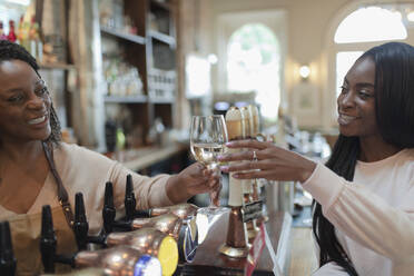 Freundlicher Barkeeper serviert einer Frau in einer Kneipe Weißwein - CAIF30797