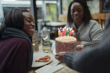 Waitress serving birthday cake to mother and daughter in restaurant - CAIF30800