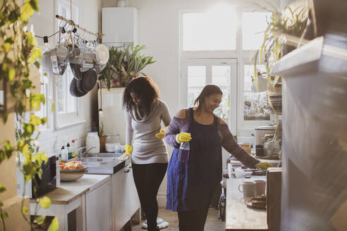 Mutter und Tochter mit Gummihandschuhen beim Reinigen der Küche - CAIF30812