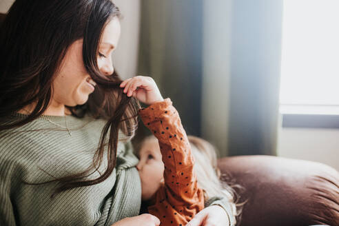 Mutter, die ihre kleine Tochter im heimischen Kinderzimmer stillt - CAVF94093