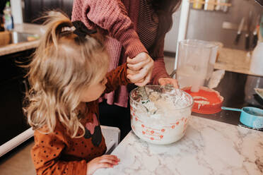 Mother and daughter feeding sour dough starter in the kitchen - CAVF94098