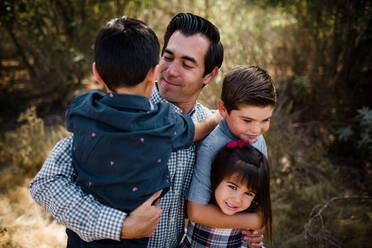 Vater hält drei Kinder auf einem Feld in San Diego - CAVF94116